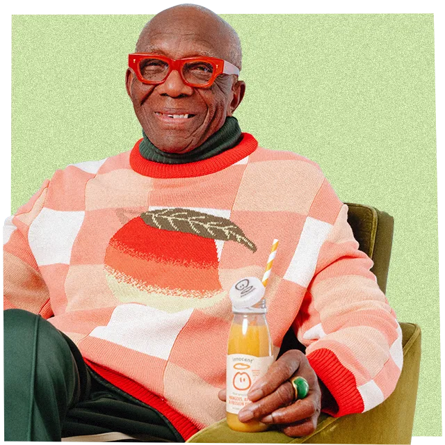 Mann trägt einen grossen Strickpullover und trinkt einen innocent Smoothie